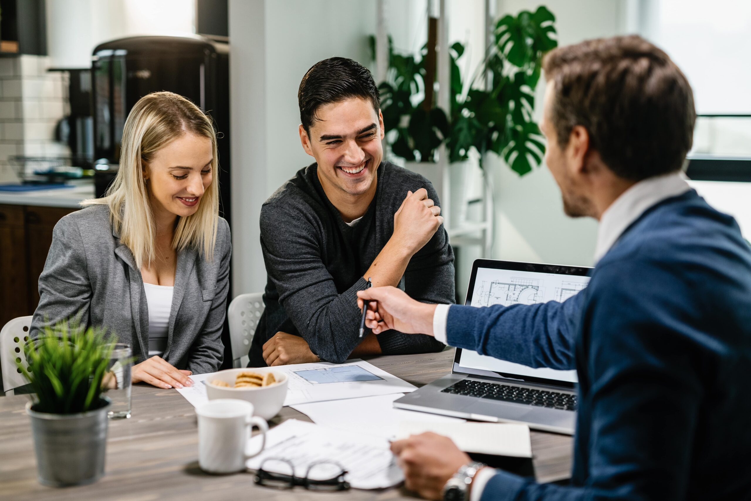 happy-couple-having-meeting-with-real-estate-agent-analyzing-blueprints-while-communicating-min